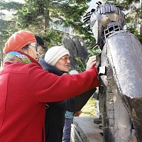 Участники экскурсии тактильно исследуют фрагмент скульптуры «Фотограф»  –  Призывник и маленькая девочка