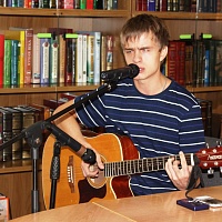 Александр Пасечник играет на гитаре и исполняет песню собственного сочинения