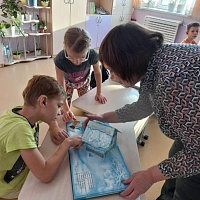 Ведущий библиотекарь ГБУК НОСБ Ольга Григорьевна демонстрирует ребятам книгу с объемными картинками - братья Гримм «Госпожа Метелица».