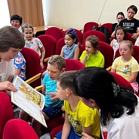 О.Г. Златковская демонстрирует ребятам иллюстрированную книгу со сказками А.С. Пушкина.