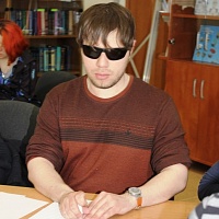 Сотрудник библиотеки И.Д. Мельников пишет диктан шрифтом Брайля, используя прибор и грифель