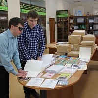 Сотрудники библиотеки И.Д. Мельников и А.П. Сокмаров в читальном зале за просмотром книг, написанных рельефно-точечным шрифтом