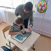 О.Г. Златковская совместно с одним из учеников рассматривает книгу с изображением морских млекопитающих