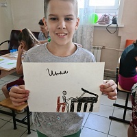 Воспитанник «Специальной (коррекционной) школы № 5 позирует с рисунком - человечек играет на пианино, подпись «Иьля» (порядок букв автора сохранен).