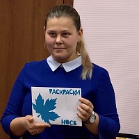 Виктория Александровна Сартакова (сотрудник библиотеки) демонстрирует конверт с раскрасками для закрепления полученных знаний