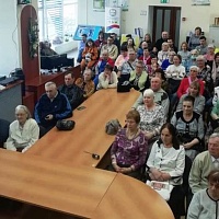 Участники встречи сидят на своих местах в читальном зале ГБУК НОСБ. Вид сверху.